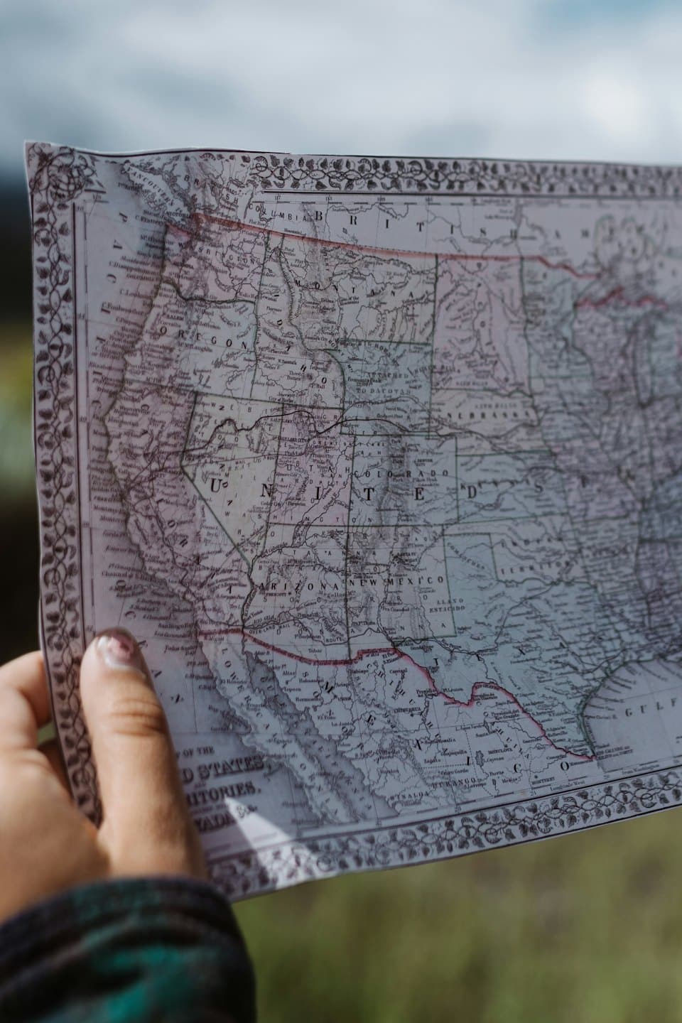 A hand holds a detailed vintage map of North America.