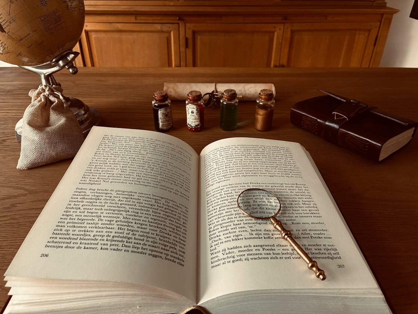 A magnifying glass rests on an open book upon a desk.