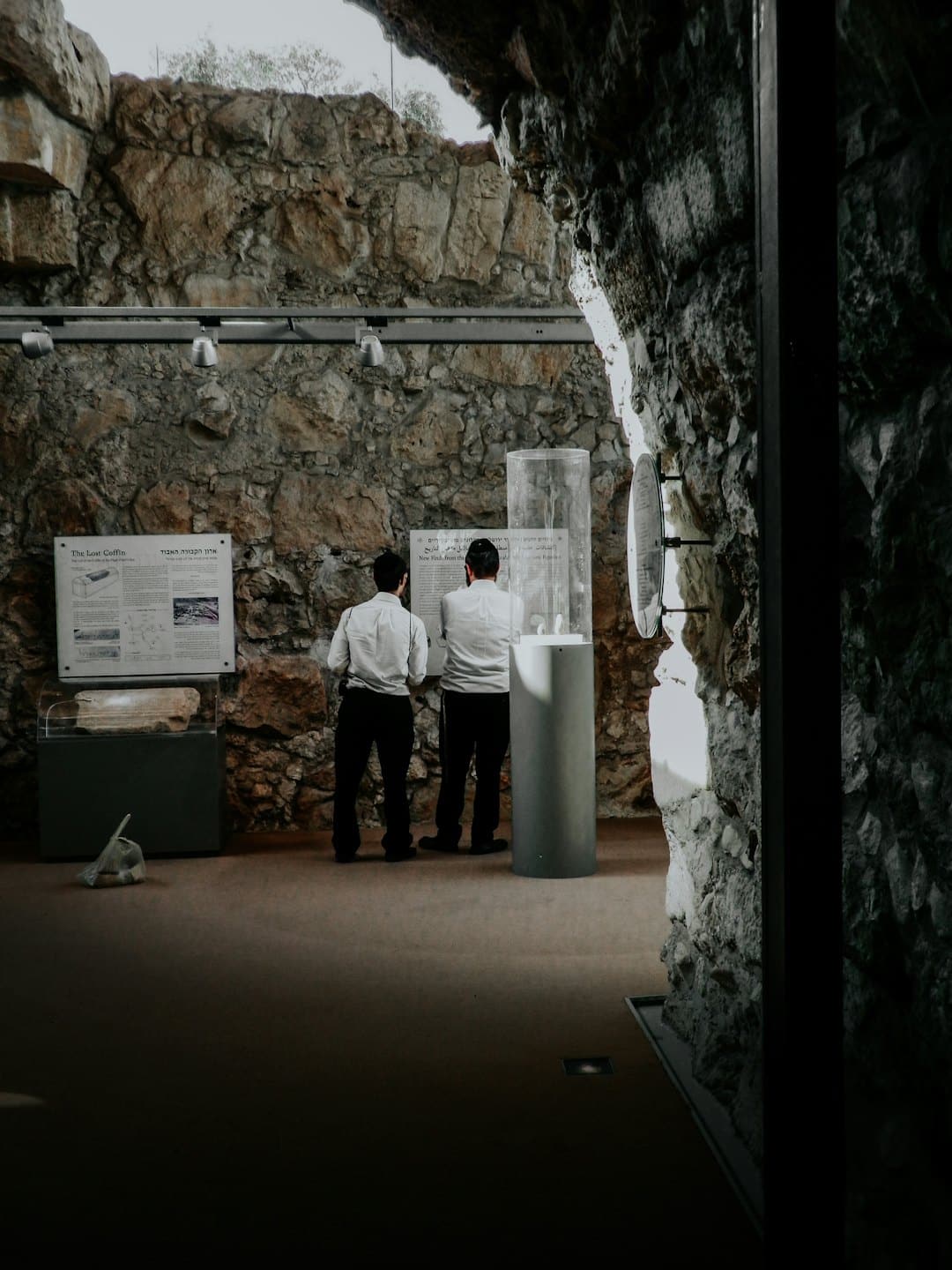Men look at museum display inside stone building.