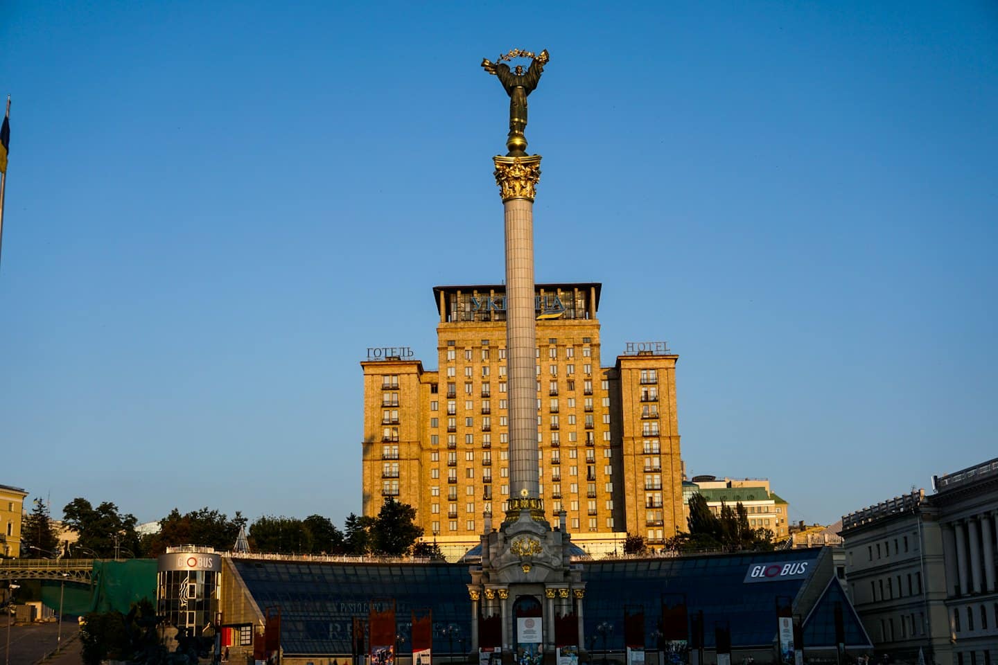A golden monument stands before a large city hotel.