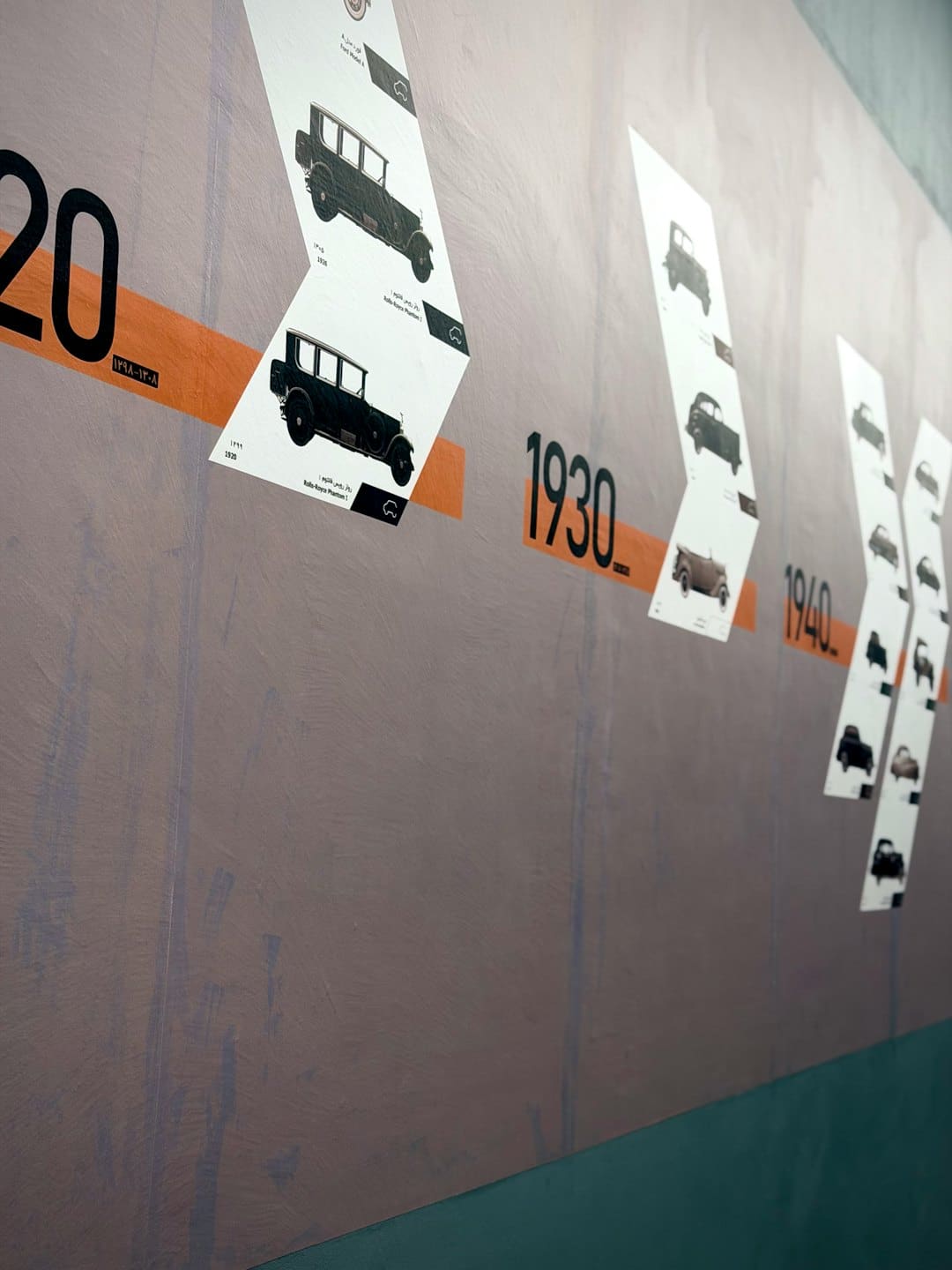 Historical timeline display with car illustrations on a textured wall.